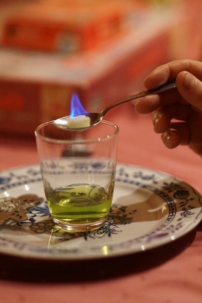Een glaasje Absint met een brandend suikerklontje op een lepel boven het glas.